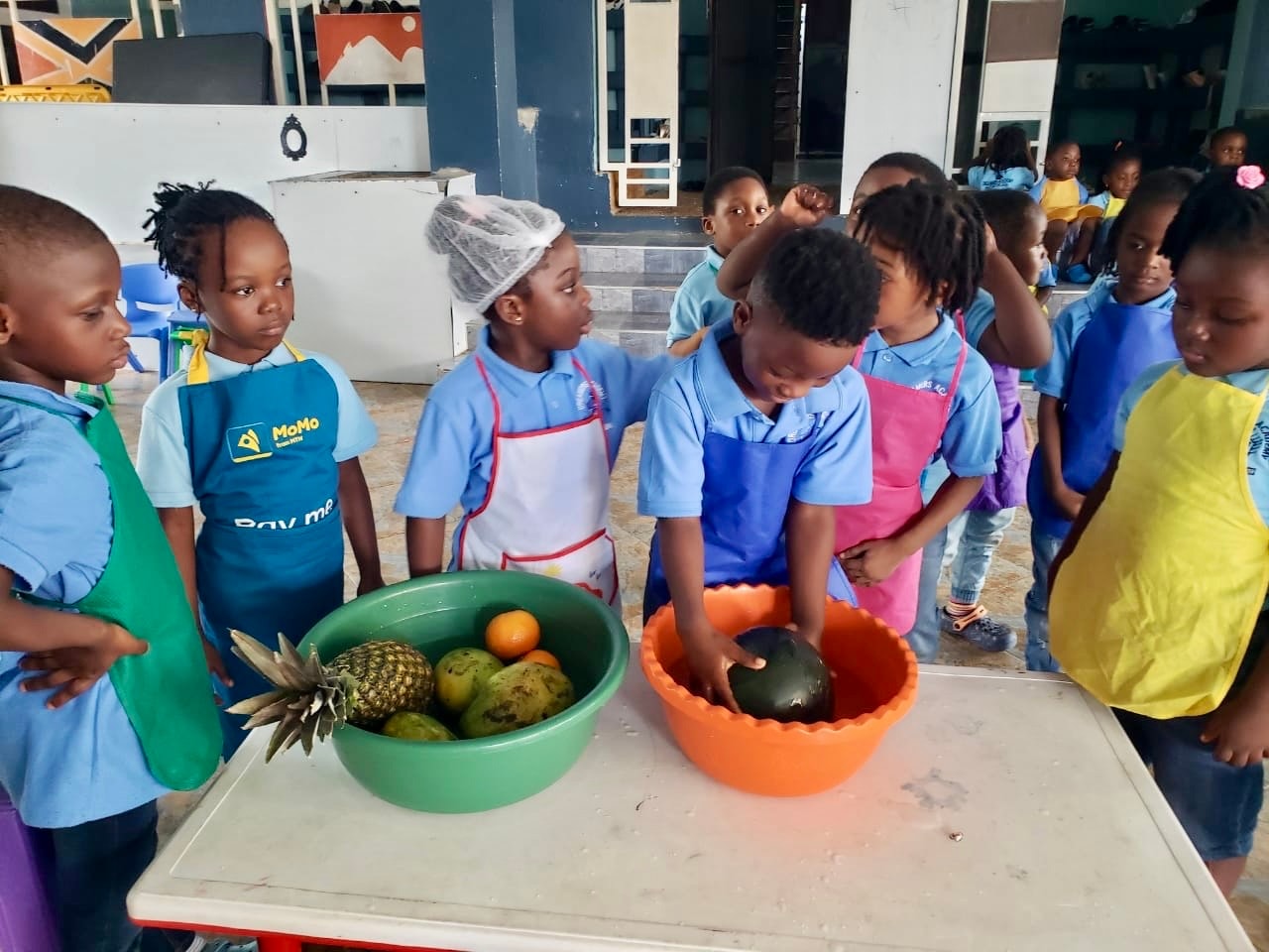 Students gathered around a table washing fresh fruit