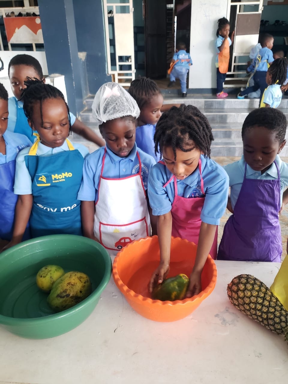 Students posing with fruits and kitchen tools before cooking